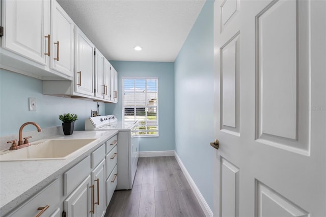 laundry area with cabinets, washer and dryer, sink, and wood-type flooring