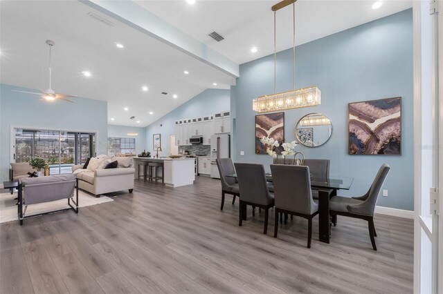 dining space featuring light hardwood / wood-style flooring, sink, ceiling fan, and high vaulted ceiling