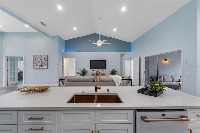 kitchen with lofted ceiling, sink, white cabinetry, ceiling fan, and light stone countertops