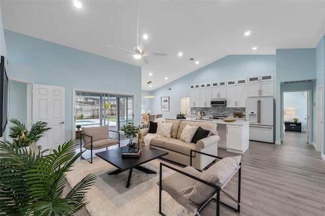 living room with ceiling fan, light wood-type flooring, and high vaulted ceiling