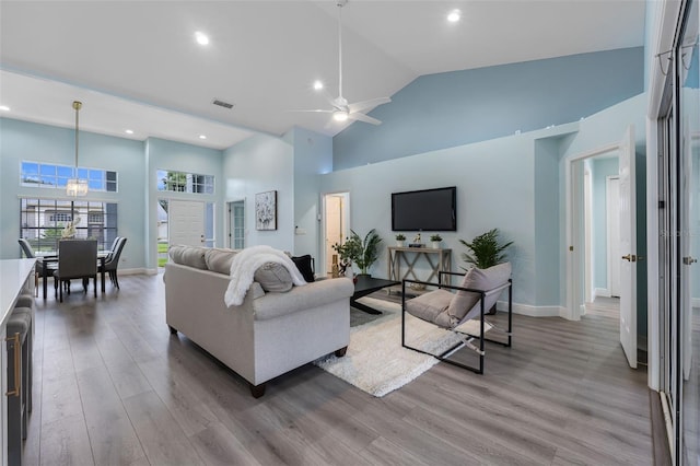 living room with ceiling fan, high vaulted ceiling, and light hardwood / wood-style flooring