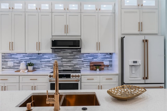 kitchen with decorative backsplash, white cabinetry, light stone countertops, and high end appliances