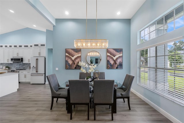 dining area featuring wood-type flooring, a notable chandelier, and a towering ceiling