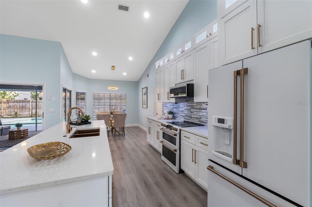 kitchen featuring pendant lighting, white cabinetry, high end appliances, light hardwood / wood-style flooring, and sink