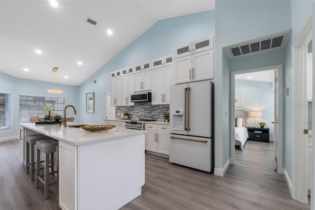 kitchen featuring white cabinets, a kitchen island with sink, light wood-type flooring, sink, and high end appliances