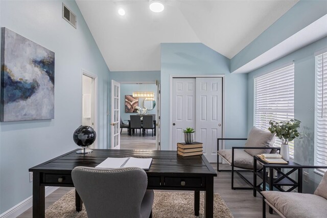 home office featuring light wood-type flooring, lofted ceiling, and an inviting chandelier