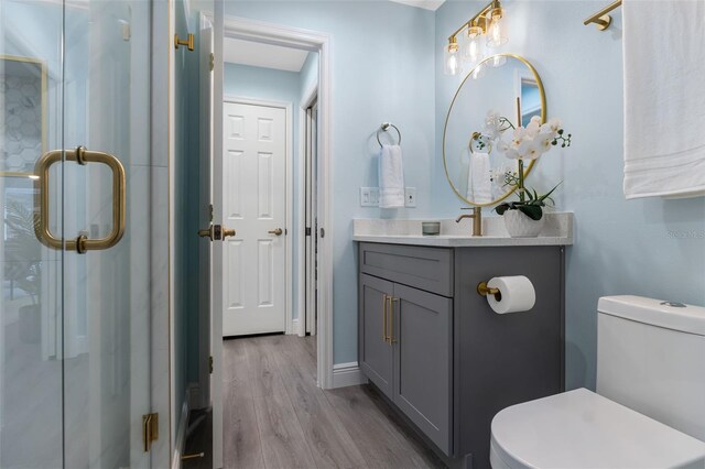 bathroom with walk in shower, wood-type flooring, vanity, and toilet