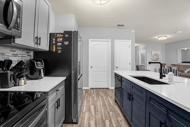 kitchen featuring a textured ceiling, decorative backsplash, black dishwasher, and sink