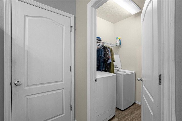 clothes washing area featuring washer and clothes dryer, light hardwood / wood-style flooring, and a textured ceiling