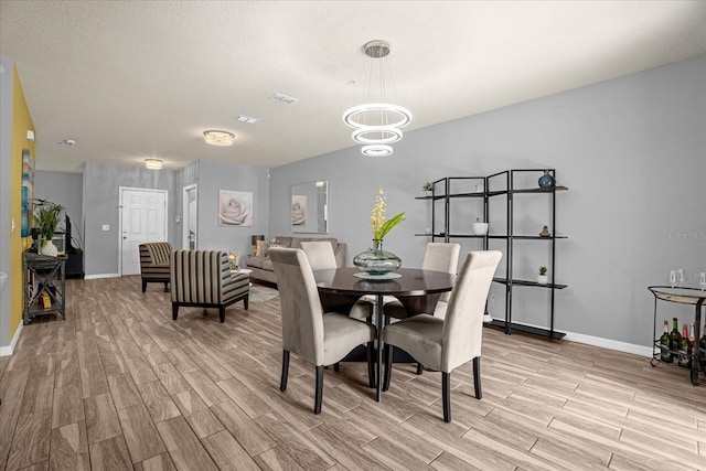 dining space with wood finish floors, a notable chandelier, and baseboards