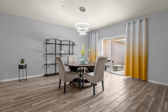 dining space with baseboards, a textured ceiling, an inviting chandelier, and wood tiled floor