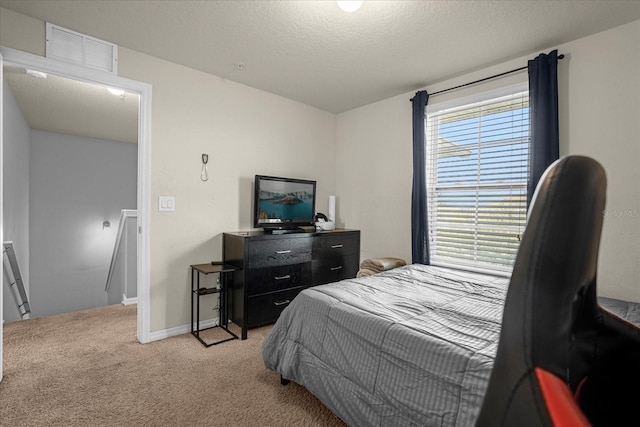 bedroom featuring baseboards, visible vents, a textured ceiling, and light colored carpet