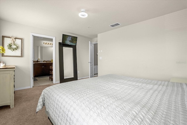 bedroom with light colored carpet, ensuite bath, and sink