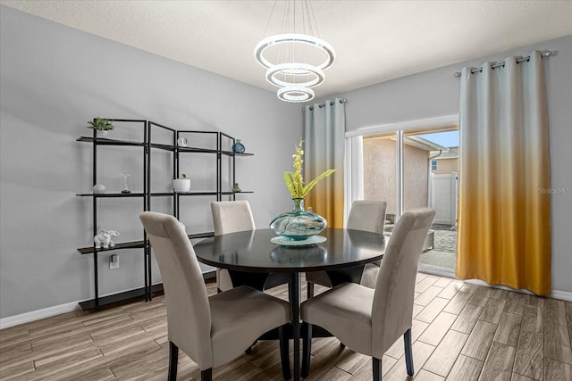 dining area with baseboards, a notable chandelier, and wood finish floors