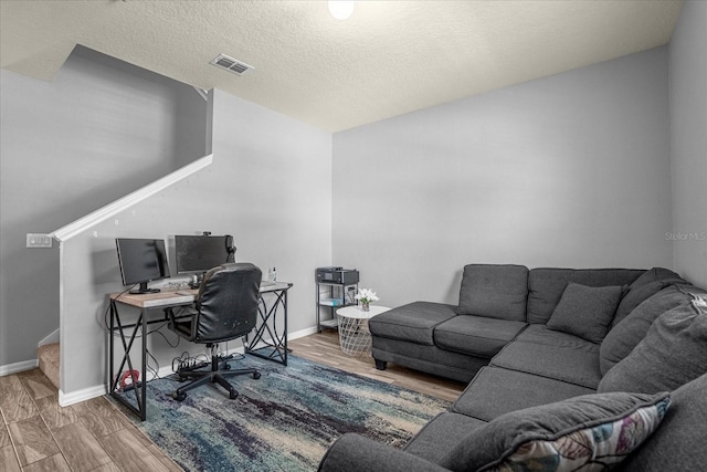 office area with visible vents, a textured ceiling, baseboards, and wood finished floors