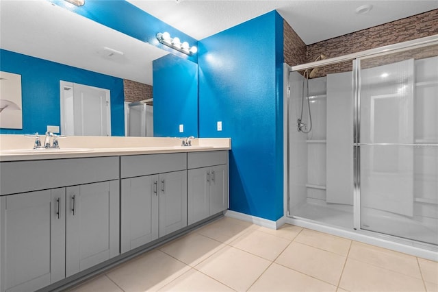 bathroom with dual vanity, a shower with shower door, and tile patterned floors