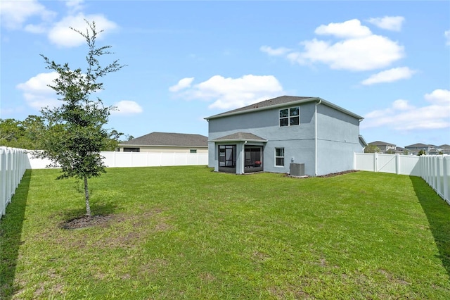 back of property featuring central air condition unit and a yard