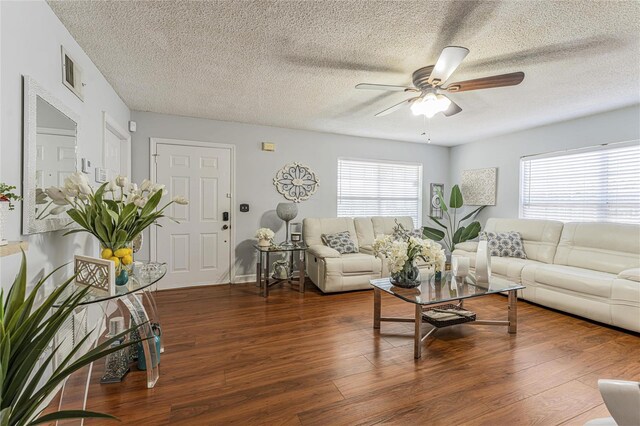 living area with dark wood-type flooring, visible vents, a textured ceiling, and a ceiling fan