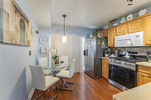 kitchen with light countertops, appliances with stainless steel finishes, decorative backsplash, dark wood-style floors, and decorative light fixtures