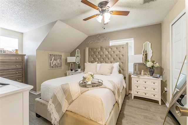 bedroom with a textured ceiling, ceiling fan, and light wood-style floors