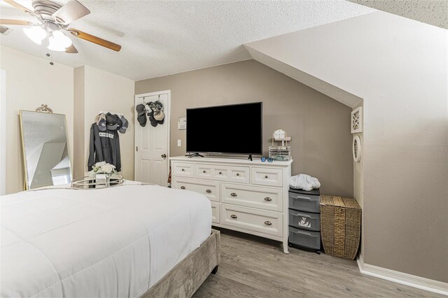 bedroom with a textured ceiling, light wood finished floors, visible vents, and a ceiling fan