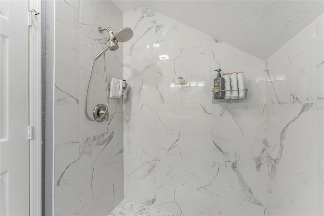 full bath featuring lofted ceiling, a textured ceiling, and a marble finish shower