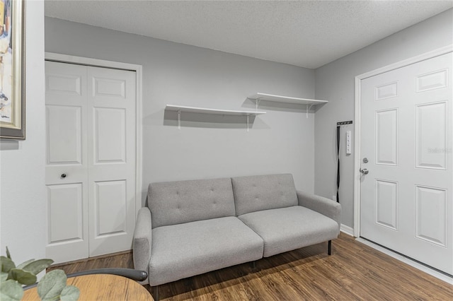 sitting room with attic access, a textured ceiling, baseboards, and wood finished floors