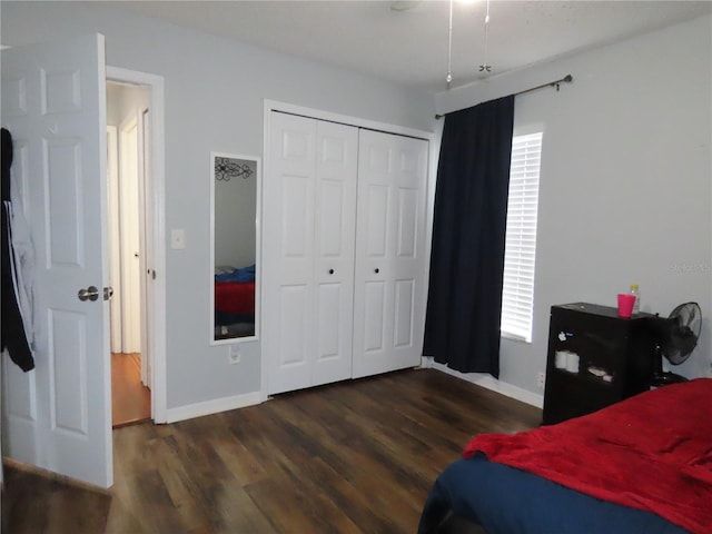 bedroom with dark wood-type flooring, a closet, and baseboards