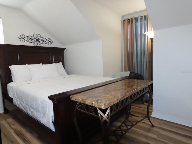 bedroom featuring lofted ceiling and dark wood finished floors