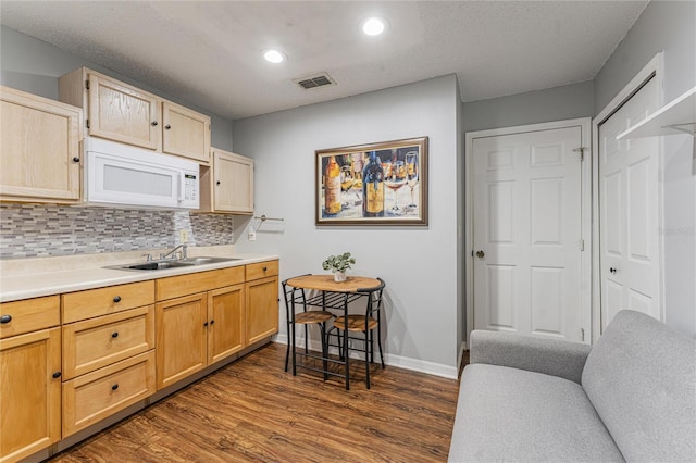 kitchen featuring light brown cabinets, dark wood-style flooring, a sink, visible vents, and light countertops