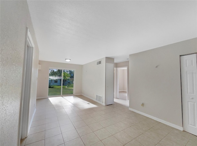 tiled empty room featuring a textured ceiling