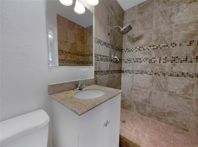 bathroom with vanity, toilet, and a tile shower