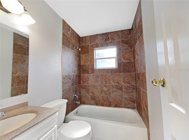 full bathroom featuring vanity, tiled shower / bath, and toilet