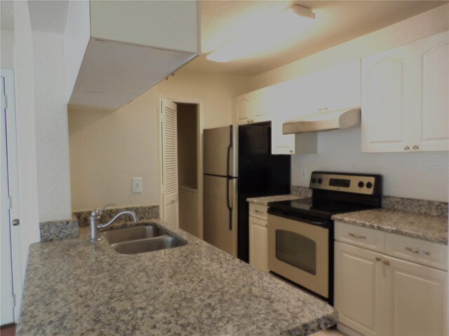 kitchen featuring stainless steel refrigerator, range with electric cooktop, sink, and white cabinets