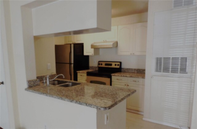 kitchen with electric stove, sink, light stone counters, kitchen peninsula, and stainless steel refrigerator