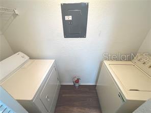 clothes washing area with dark hardwood / wood-style flooring, separate washer and dryer, and electric panel