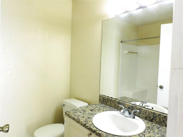 bathroom with a shower, vanity, and toilet