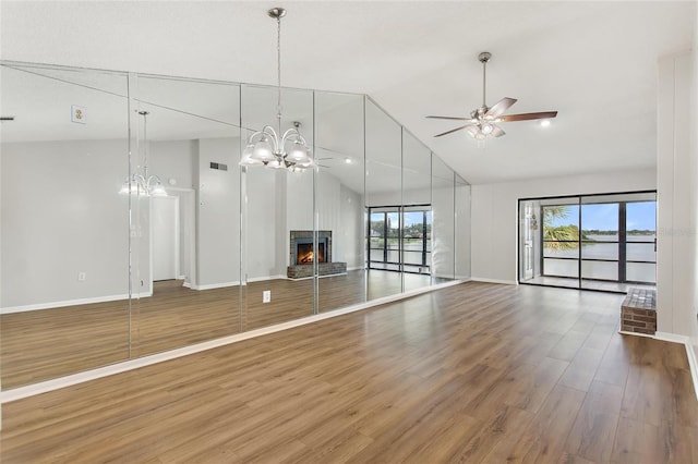 unfurnished living room featuring ceiling fan with notable chandelier, wood-type flooring, and high vaulted ceiling