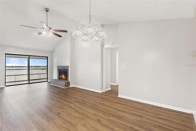 unfurnished living room featuring hardwood / wood-style flooring, ceiling fan with notable chandelier, a brick fireplace, and high vaulted ceiling