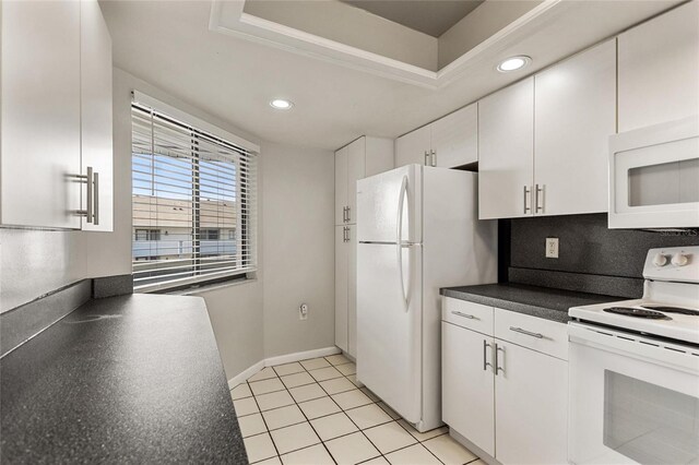 kitchen featuring a tray ceiling, white cabinets, decorative backsplash, white appliances, and light tile patterned floors