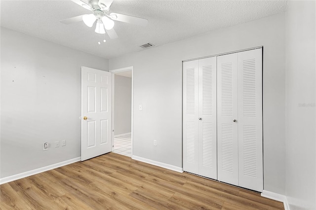 unfurnished bedroom with a closet, a textured ceiling, ceiling fan, and light wood-type flooring