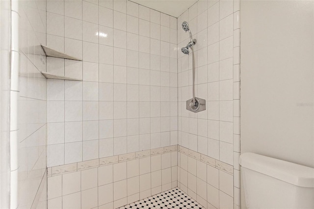 bathroom featuring tiled shower and toilet