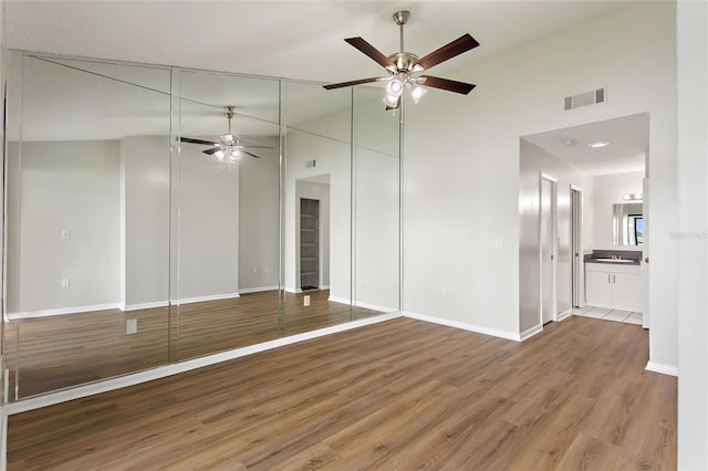 unfurnished bedroom featuring high vaulted ceiling, ensuite bathroom, and hardwood / wood-style flooring