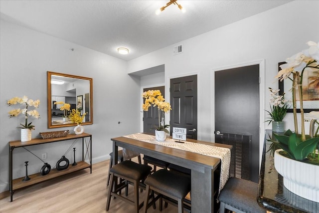 dining area with a textured ceiling and wood-type flooring