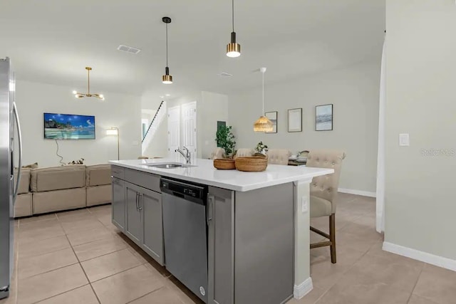 kitchen featuring sink, light tile patterned flooring, dishwasher, and a center island with sink