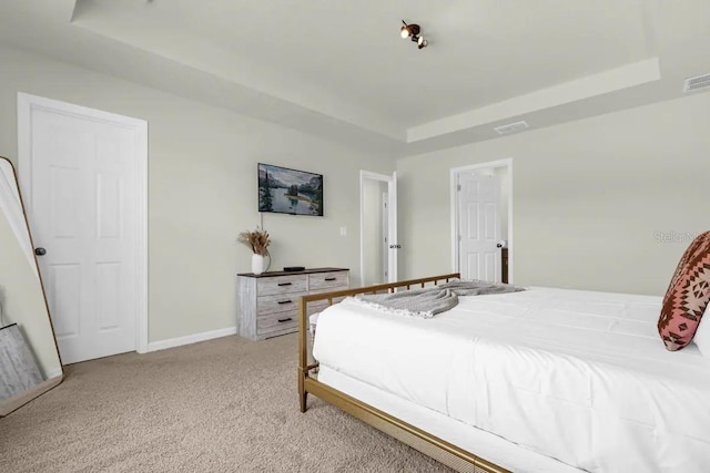 bedroom with light carpet and a raised ceiling