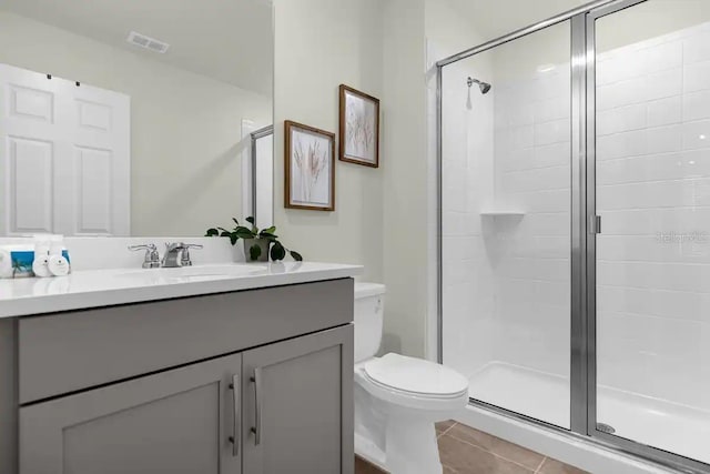 bathroom with tile patterned floors, vanity, an enclosed shower, and toilet