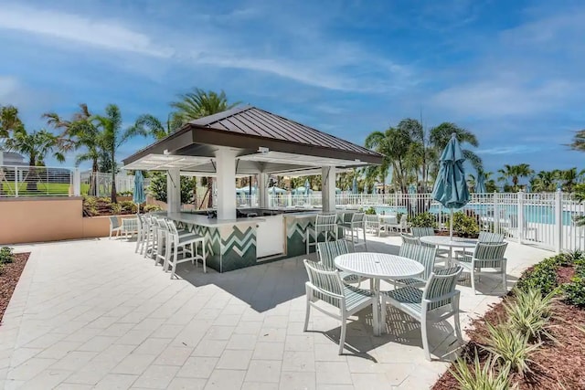 view of patio with a bar and a community pool