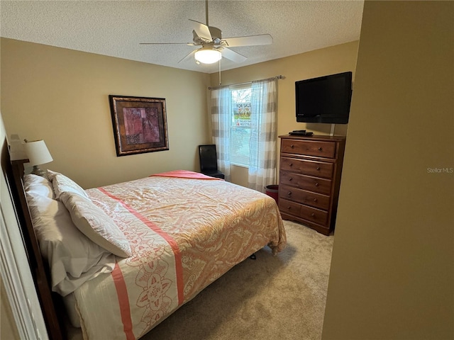 bedroom with ceiling fan, light colored carpet, and a textured ceiling