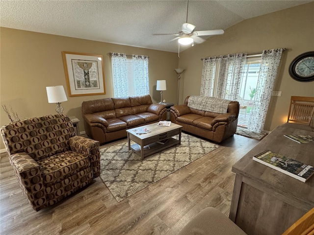 living room with hardwood / wood-style floors, vaulted ceiling, a textured ceiling, and ceiling fan